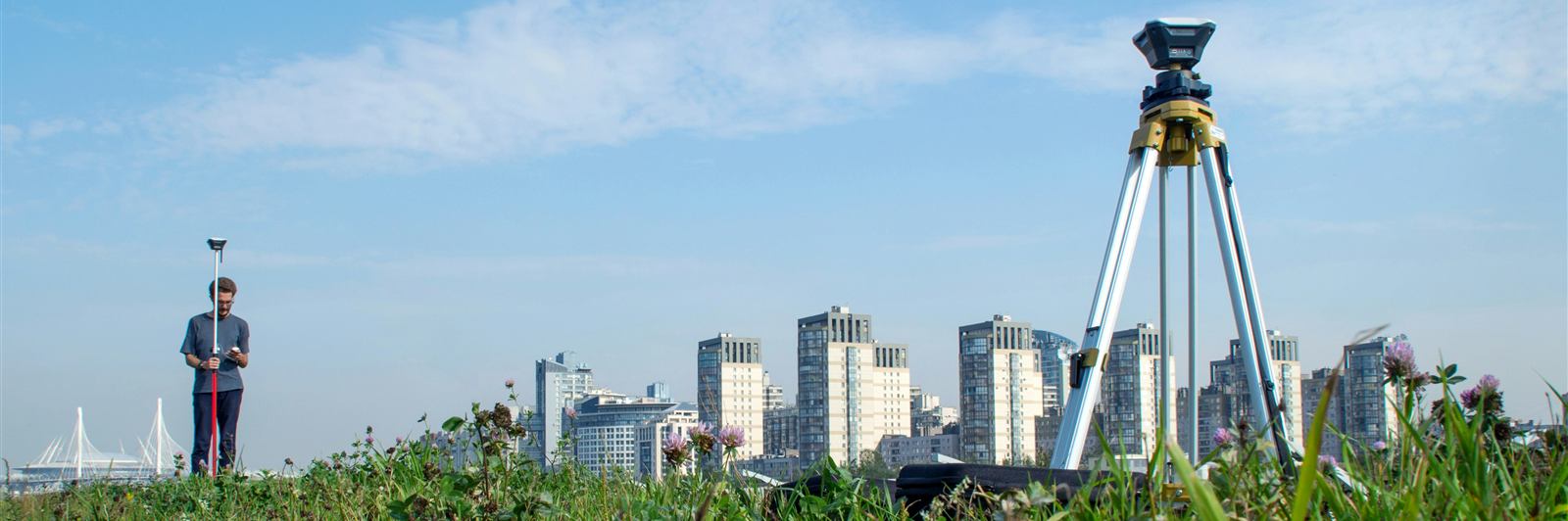 Survey crew with a total station overlooking a city skyline